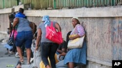 FILE—Pedestrians take cover during clashes between police and gang members in Port-au-Prince, Haiti, March 1, 2024.