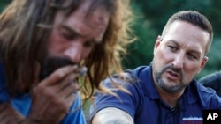 FILE - Pastor Jamie Casey, right, speaks with Brian Peets at a homeless camp in New Bedford, Mass., Aug. 10, 2018.