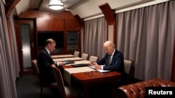 El presidente Joe Biden (derecha) sentado en un tren con el asesor de Seguridad Nacional Jake Sullivan mientras repasa su discurso con motivo del primer aniversario de la guerra en Ucrania, el lunes 20 de febrero de 2023, antes de llegar a Kiev. 