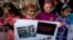 FILE - Pakistani children hold a placard showing pictures of Peshawar's school attack victims during a demonstration in connection with first anniversary of the school attack, Dec. 15, 2015.