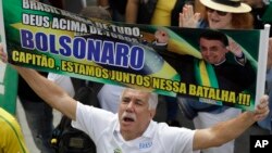 A supporter of Brazil's President Jair Bolsonaro holds up a message in Portuguese: "Bolsonaro, captain, we are in this battle together," on Copacabana beach in Rio de Janeiro, Brazil, May 26, 2019. 