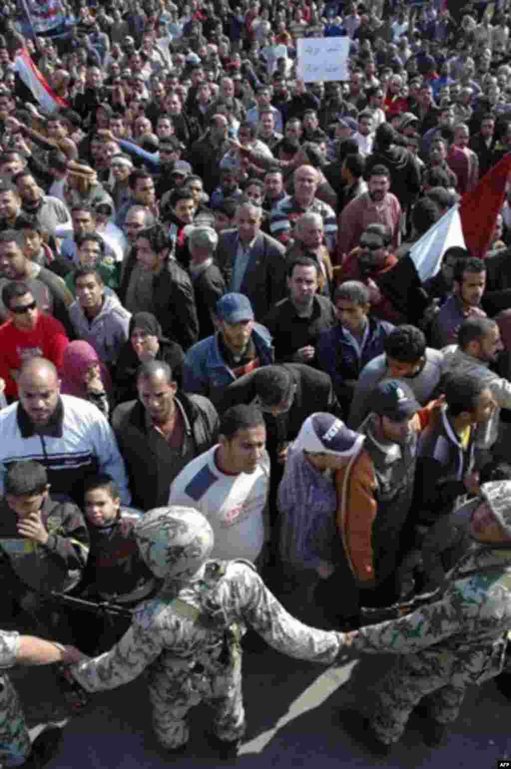 Egyptian army soldiers guard anti-government protesters as they march in Suez, Egypt, Friday, Feb. 11, 2011. Egypt's military threw its weight Friday behind President Hosni Mubarak's plan to stay in office through September elections while protesters fann