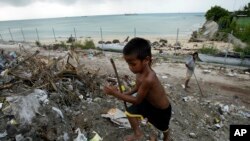 FILE - A boy scavenges for saleable items at Red Beach dump, on Tarawa atoll, Kiribati, March 30, 2004