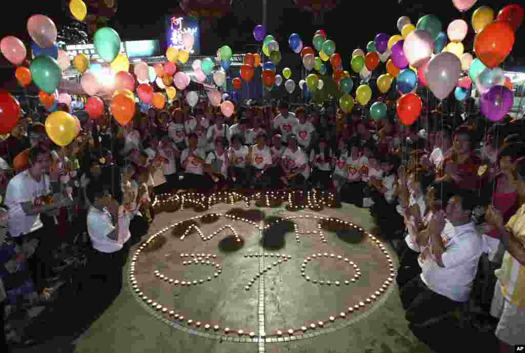 People holding balloons pose next to a message reading "Pray for MH370" in Kuala Lumpur, March 17, 2014.