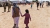 FILE - A man walks with a child through Fort Bliss' Doña Ana Village where Afghan refugees were being housed, in New Mexico, Sept. 10, 2021. 