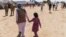FILE - A man walks with a child through Fort Bliss' Doña Ana Village where Afghan refugees were being housed, in New Mexico, Sept. 10, 2021. 