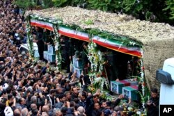 Para pelayat berkumpul di sekitar truk yang membawa peti jenazah Presiden Iran Ebrahim Raisi dan rekan-rekannya yang tewas dalam kecelakaan helikopter di wilayah pegunungan di barat laut Iran, saat upacara pemakaman di Kota Tabriz, Selasa, 21 Mei 2024. (Foto: via AP)