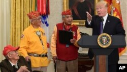 President Donald Trump, right, speaks during a meeting with Navajo Code Talkers including Fleming Begaye Sr., seated left, Thomas Begay, second from left, and Peter MacDonald, second from right, in the Oval Office of the White House, Nov. 27, 2017. 