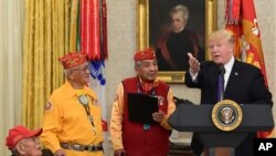 President Donald Trump, right, speaks during a meeting with Navajo Code Talkers including Fleming Begaye Sr., seated left, Thomas Begay, second from left, and Peter MacDonald, second from right, in the Oval Office of the White House, Nov. 27, 2017. 