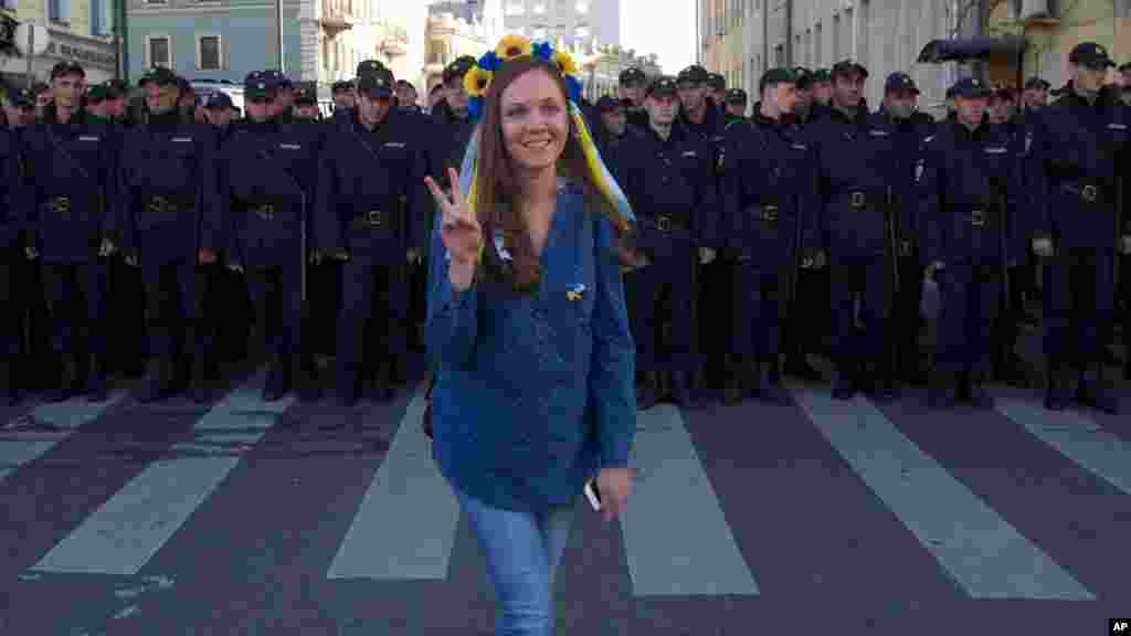 A woman wearing traditional Ukrainian flower headband poses for a photo in front of police officers, during an anti-war rally in downtown Moscow, Russia, Sept. 21, 2014. 