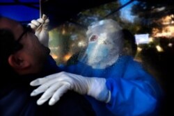 Separated by a plastic barrier, Nurse Mariel Portillo takes a swab sample from a man for a COVID-19 test outside the General Hospital in Luque, Paraguay, June 11, 2021.