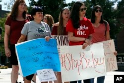 Sonja Breda, 23, right, holds a sign saying "Stop Betsy" as a group of survivors of sexual violence and their supporters gather to protest proposed changes to Title IX before a speech by Education Secretary Betsy DeVos, Sept. 7, 2017, at the George Mason University Arlington, Va., campus.