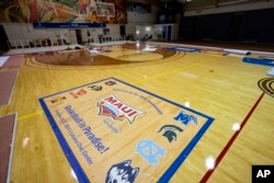 Workers set up banners and signs at Lahaina Civic Center, the venue for the Maui Invitational in Lahaina on the island of Maui in Hawaii, Nov. 18, 2024.