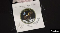 An Apollo 11 emblem, flown into lunar orbit and signed by the crew - Neil Armstrong, Michael Collins, and Buzz Aldrin, which is estimated at $40,000 to $60,000, is displayed as part of the upcoming Space History Sale at Bonham's auction house in New York, April 4, 2014.