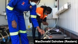 Employees charge lithium ion batteries for a Hamba electric motorcycle at a solar-powered recharging station in Wedza, Zimbabwe, 22 May 2020. Picture taken May 22, 2020. REUTERS/MacDonald Dzirutwe