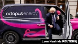 Perdana Menteri Inggris Boris Johnson berfoto dengan taksi listrik saat mengunjungi markas Octopus Energy, di London, Inggris, 5 Oktober 2020. (Foto: Leon Neal via REUTERS)