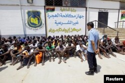 FILE - Migrants sit at the Tajoura branch of the Anti-Illegal Immigration Authority, in Tajoura, Libya, Aug. 6, 2017.