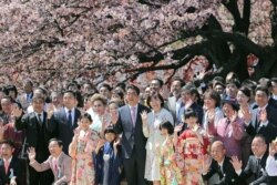 FILE - Japanese Prime Minister Shinzo Abe, center left, and his wife Akie, center right, pose for pictures with their guests during his cherry blossom viewing party at a park in Tokyo, April 13, 2019.