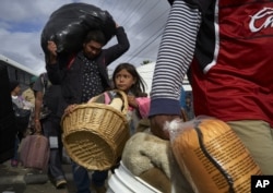 La niña Brittany Ríos, de Honduras y parte de la caravana de migrantes que busca asilo en Estados Unidos, lleva animales de peluche en una canasta de mimbre, el viernes 30 de noviembre de 2018, en Tijuana, México.