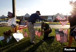 Mourners places flags at a growing memorial in front of the Armed Forces Career Center in Chattanooga, Tennessee, July 16, 2015.