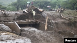 FILE - People cross a bridge broken by heavy rains and landslides in the village of Sebit, West Pokot County, Kenya, Nov. 24, 2019.