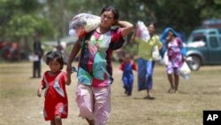 Thai women and children walk to a waiting bus to transport them home after sporadic fighting between Thai and Cambodian troops was reported at a refugee camp in Surin province, northeastern Thailand, May 2, 2011