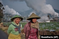 Farmers walk by as steam rises from a geothermal power plant in Dieng, Central Java, Indonesia, Nov. 15, 2024. (AP Photo/Beawiharta)