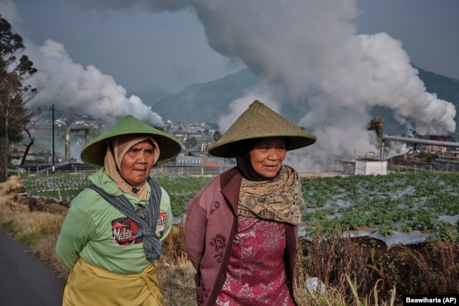 Farmers walk by as steam rises from a geothermal power plant in Dieng, Central Java, Indonesia, Nov. 15, 2024. (AP Photo/Beawiharta)