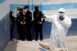 An employee of the Guatemala's Health Ministry, wearing a protective suit and a mask, gestures at a temporary shelter for Guatemalan migrants who arrived in the country on U.S. deportation flights, in Guatemala City, April 16, 2020.