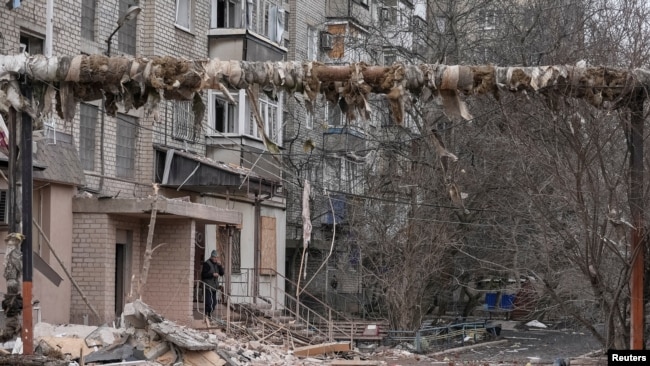 A resident smokes near his apartment building damaged by Russian military strikes, amid Russia's attack on Ukraine, in the frontline town of Pokrovsk in Donetsk region, Ukraine, March 6, 2025.