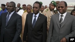 Dioncounda Traore, center, Mali's parliamentary head who was forced into exile after last month's coup, walks with Burkina Faso's Foreign Affairs Minister Djibrill Bassole, right, as Traore arrives in Bamako to take up his constitutionally-mandated post a
