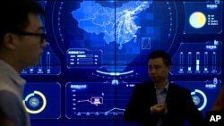 在北京举行的全球移动互联网大会上，参观者站在一个显示中国地图的电子数据显示器前(2018年4月26日)