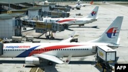 Catering service trucks (R) load inflight supplies onto Malaysia Airlines aircraft at Kuala Lumpur Intenational Airport (KLIA) in Sepang, March 25, 2014.