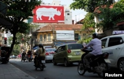 A giant poster, encouraging passers-by to stop using rhino horn, is seen on a street in Hanoi, Sept. 22, 2014.