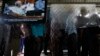 FILE - People line up to enter the Extraordinary Chambers in the Courts of Cambodia as a television screen shows former Khmer Rouge President Khieu Samphan, in Phnom Penh.