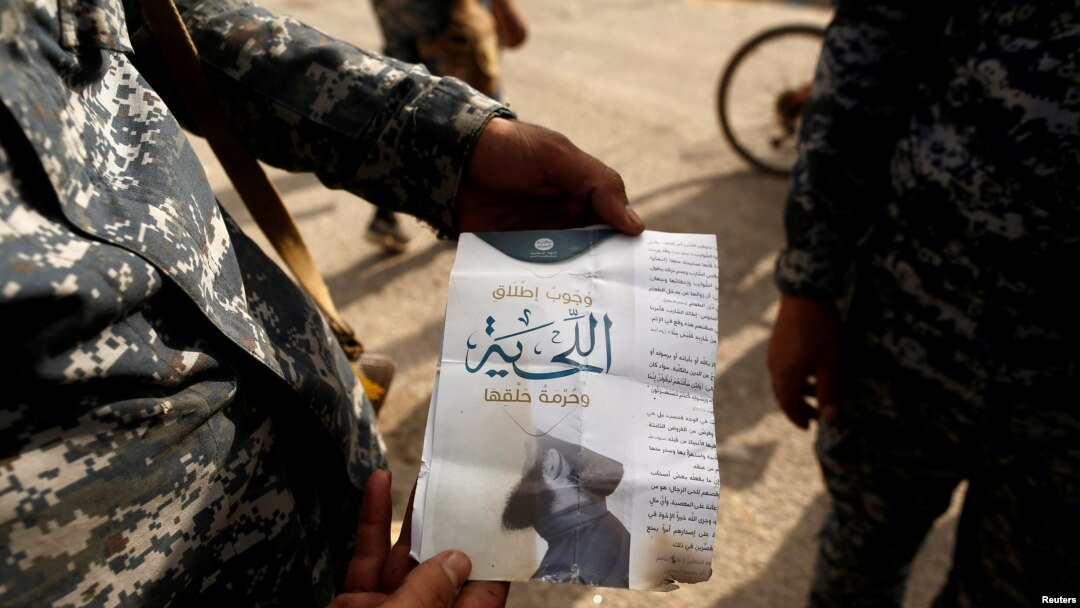Seorang tentara Irak menunjukkan pamflet bertuliskan "Berjanggut itu wajib, dilarang mencukurnya" di kota al-Shura, sebelah selatan Mosul (30/10). (Reuters/Zohra Bensemra)