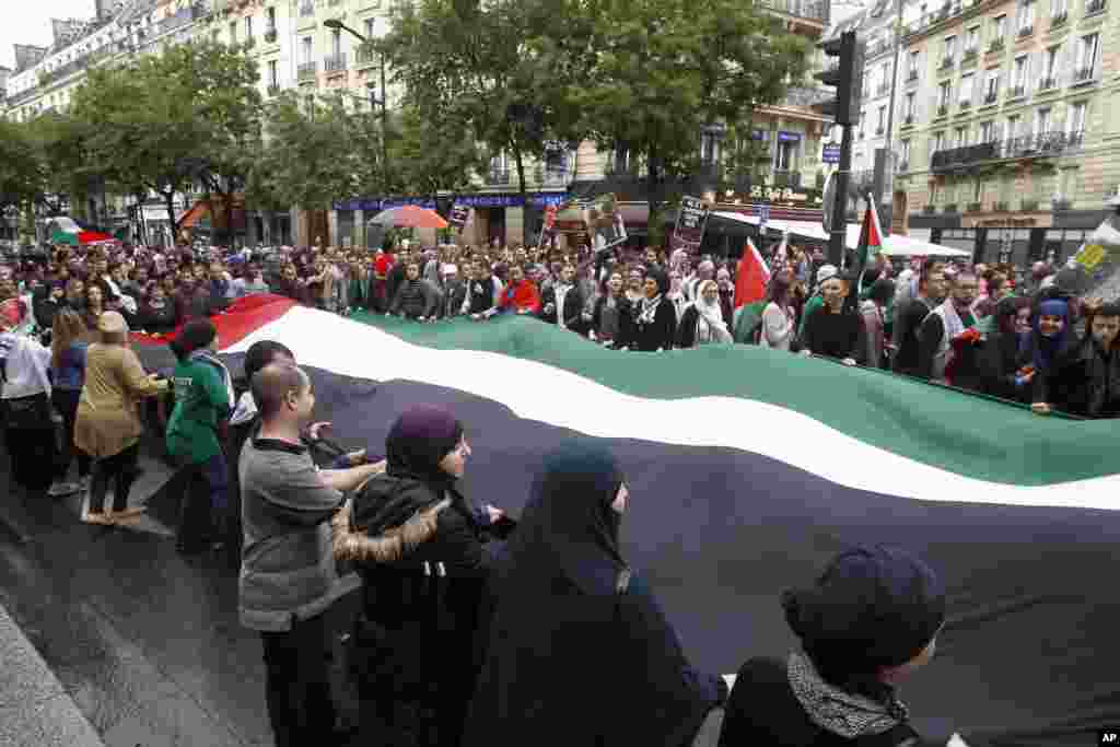 Pro-Palestinian demonstrators shake a giant flag and chant anti-Israeli slogans as they protest against Israeli air attacks in the Gaza strip, Paris, July 13, 2014.