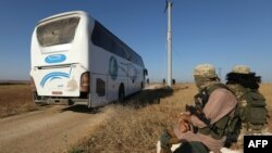 Un bus entrant, sous l'oeil de combattants djihadistes, dans Foua et Kefraya pour evacuer leurs habitants, le 18 juillet 2018.