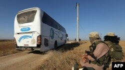 Members of Hayat Tahrir al-Sham group, led by Syria's former al-Qaida affiliate, watch as buses get ready to enter the towns of Foua and Kefraya to evacuate their residents, July 18, 2018.