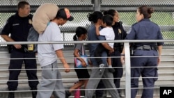 Ever Castillo, left, and his family, immigrants from Honduras, are escorted back across the border by U.S. Customs and Border Patrol agents, June 21, 2018, in Hildalgo, Texas. The parents were told they would be separated from their children.