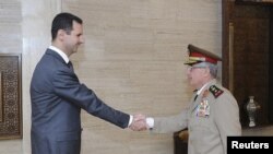 Syria's President Bashar al-Assad (L) welcomes new Chief of General Staff of the Army and the Armed Forces, General Ali Abdullah Ayyoub, before a meeting in Damascus, July 22, 2012. 