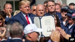President Donald Trump is surrounded by first responders after signing H.R. 1327, an act ensuring that a victims' compensation fund related to the Sept. 11 attacks never runs out of money, in Washington, July 29, 2019.