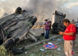 Orang-orang berdiri di dekat mobil yang rusak pasca ledakan di Beirut, Lebanon 4 Agustus 2020. (REUTERS / Issam Abdallah)
