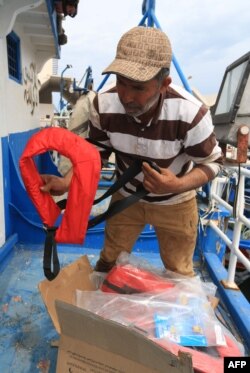 Tunisian fishermen prepare life jackets to be used in case they meet migrants in distress at sea, May 21, 2019, at the port of Zarzis, Tunisia. Most of the fishermen have already brought back migrants, saving hundreds of lives over the years.