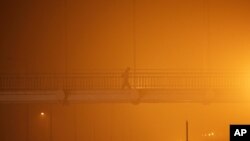 FILE - A man walks on a pedestrian bridge amidst heavy smog in New Delhi, India, Nov. 6, 2016.