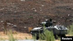 A Turkish military armoured vehicle patrols on the border line near Turkish Cilvegozu border gate, located opposite the Syrian commercial crossing point Bab al-Hawa in Reyhanli, Hatay province, Sep. 17, 2013. 
