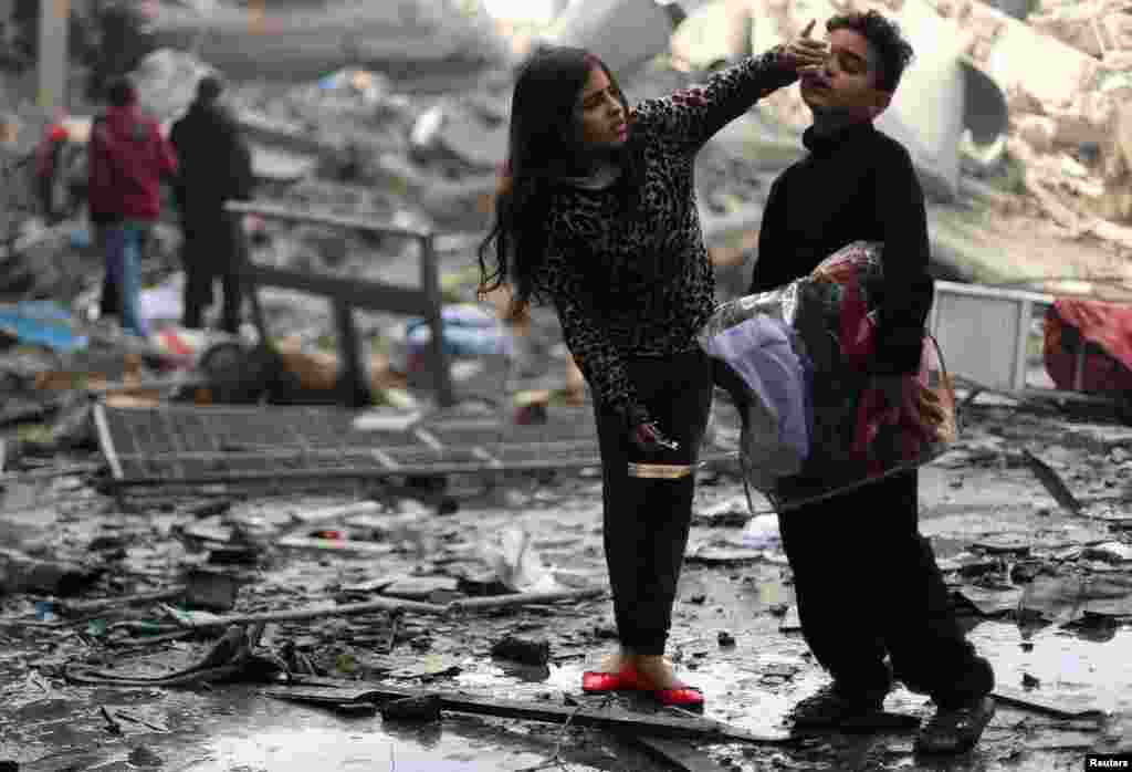 A Palestinian girl cleans her brother&#39;s face outside their destroyed house after an Israeli missile targeted a nearby Hamas site, in Gaza City, in the Gaza Strip.