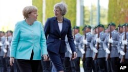 German Chancellor Angela Merkel, left, and British Prime Minister Theresa May walk on the red carpet during a military welcoming ceremony at the chancellery in Berlin Wednesday, July 20, 2016. (AP Photo/Michael Sohn)