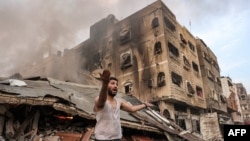 Un hombre reacciona frente a un edificio derrumbado en llamas tras el bombardeo israelí en la ciudad de Gaza el 11 de octubre de 2023.