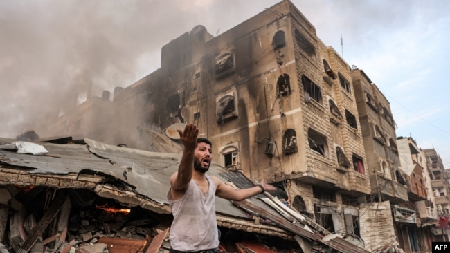 Un hombre reacciona frente a un edificio derrumbado en llamas tras el bombardeo israelí en la ciudad de Gaza el 11 de octubre de 2023.